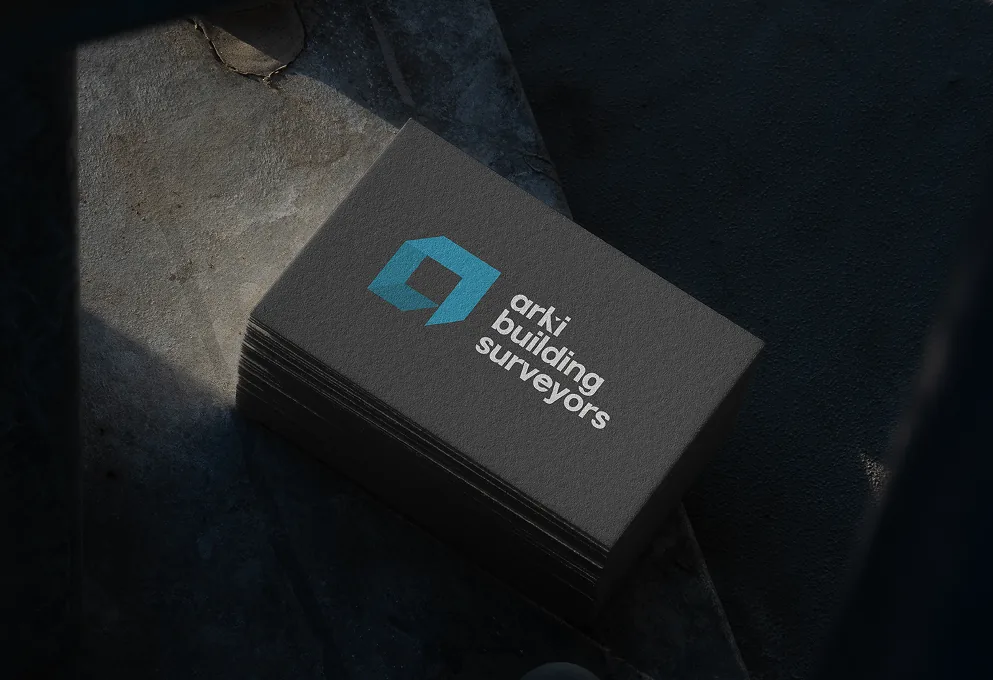 Arki Building Surveyors business cards stacked on a dark surface