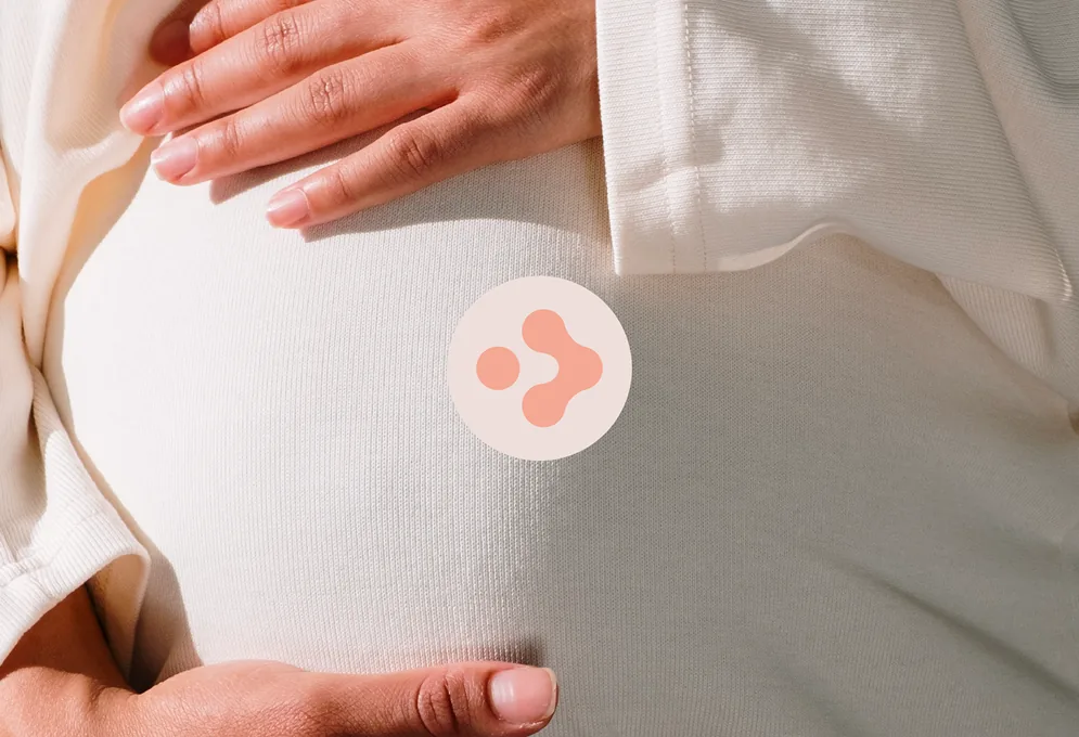 Create Fertility brand identity: the coral logomark over a close-up of hands resting on a pregnant belly
