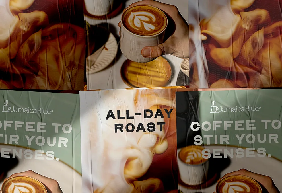 Jamaica Blue street posters: latte-art photography with the lines “Coffee to stir your senses” and “All-day roast”