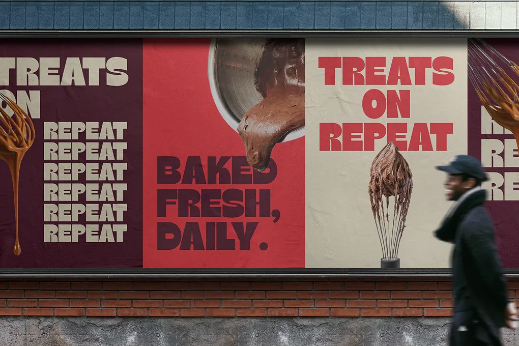 Street posters reading “Treats on repeat” and “Baked fresh, daily” as a man walks past