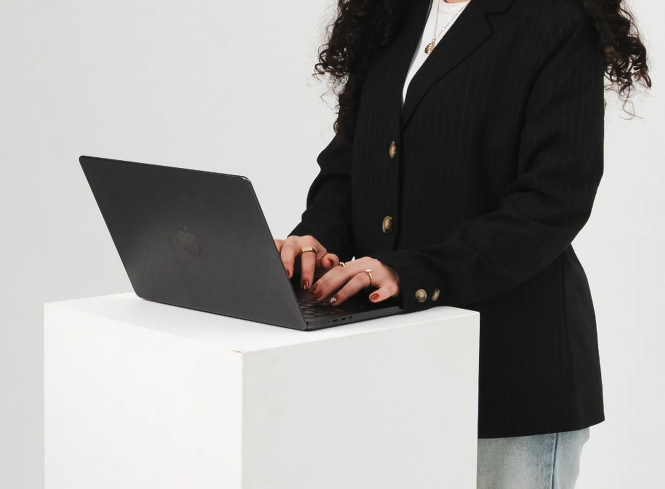 Woman in a black blazer typing on a laptop