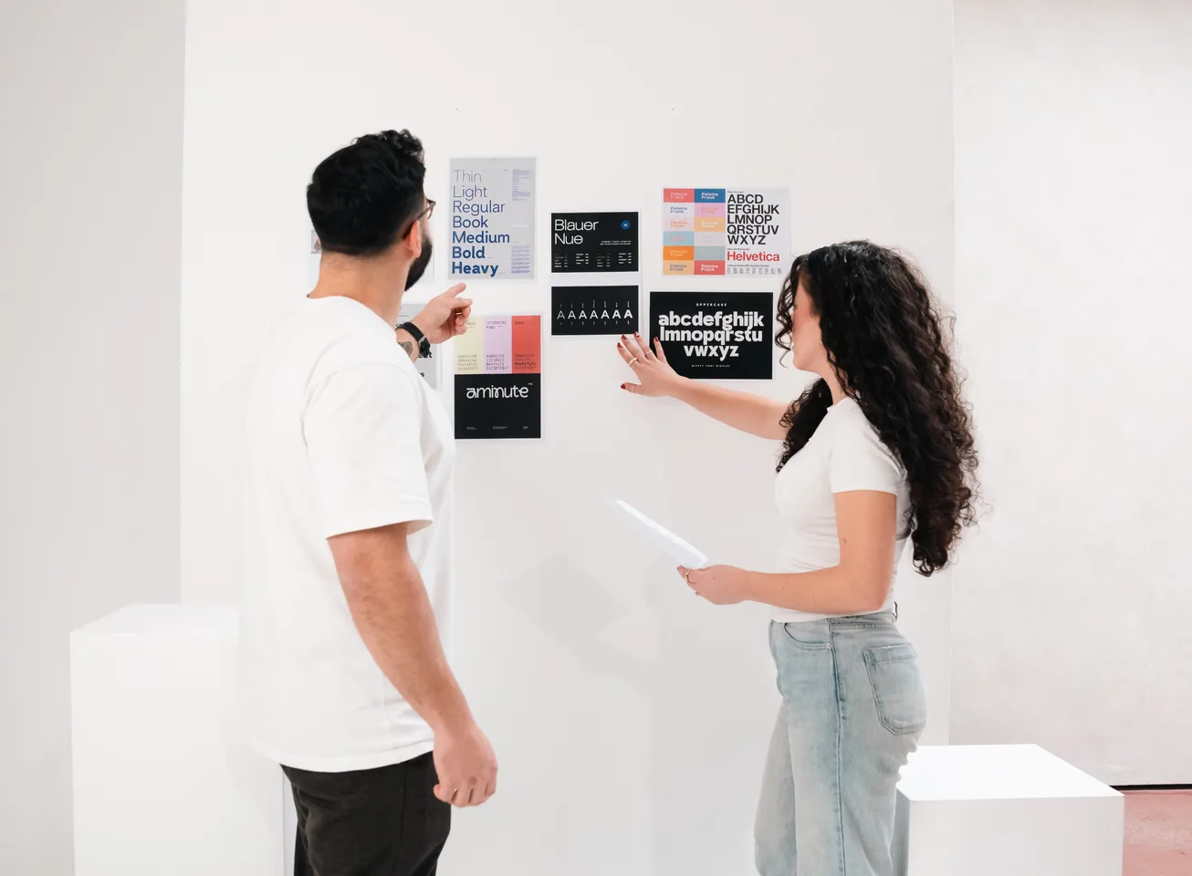 Two designers pinning type specimens to a wall