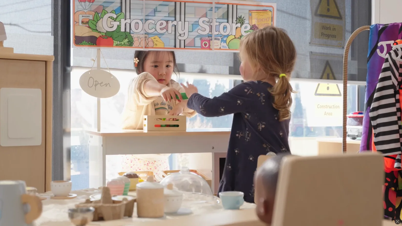 Two children playing shop at a toy grocery stall in a King Kids early learning room