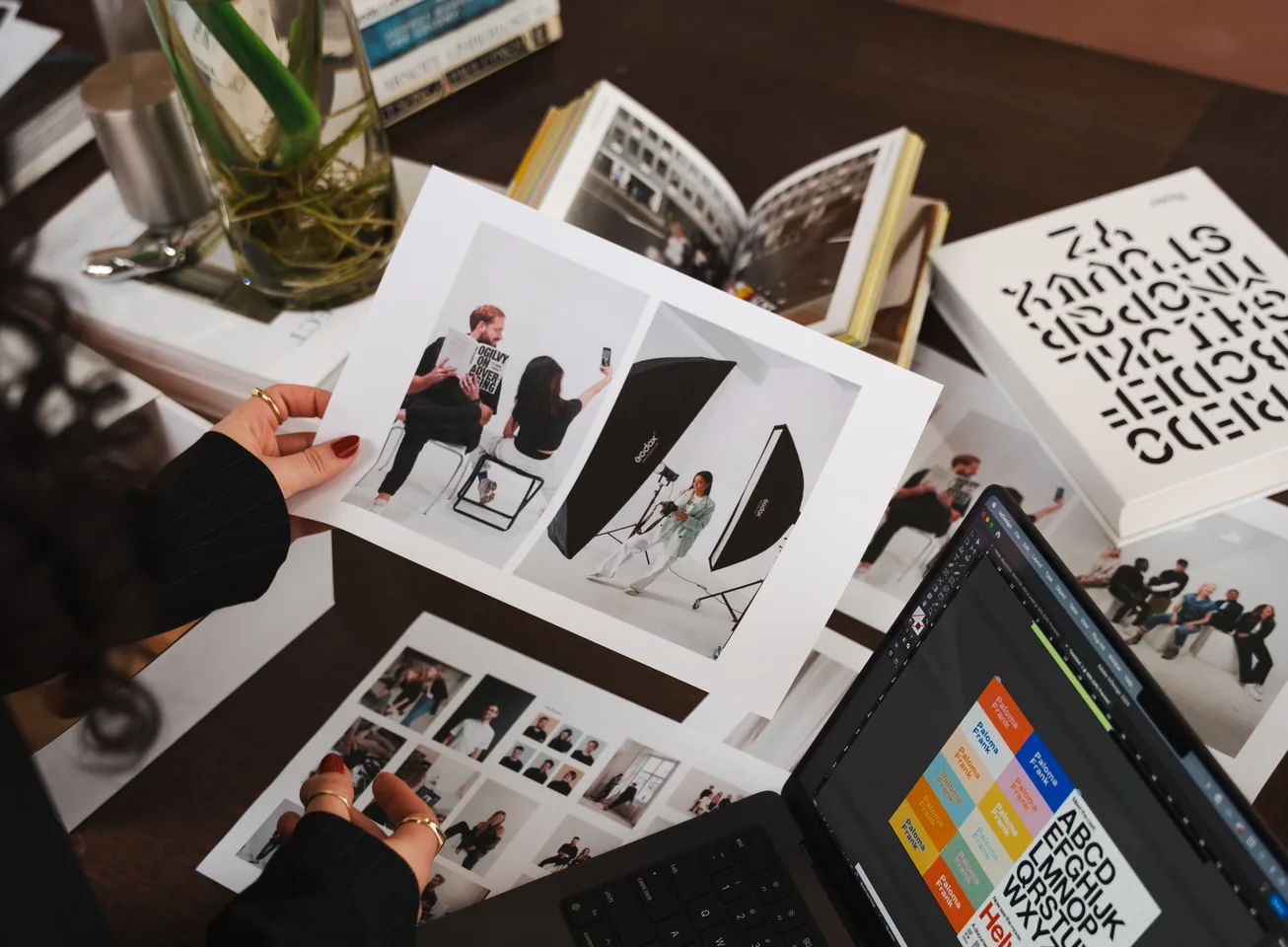 Flat-lay of printed photos, magazines and a laptop