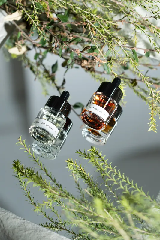 Two amber and clear dropper bottles suspended among sprigs of native foliage