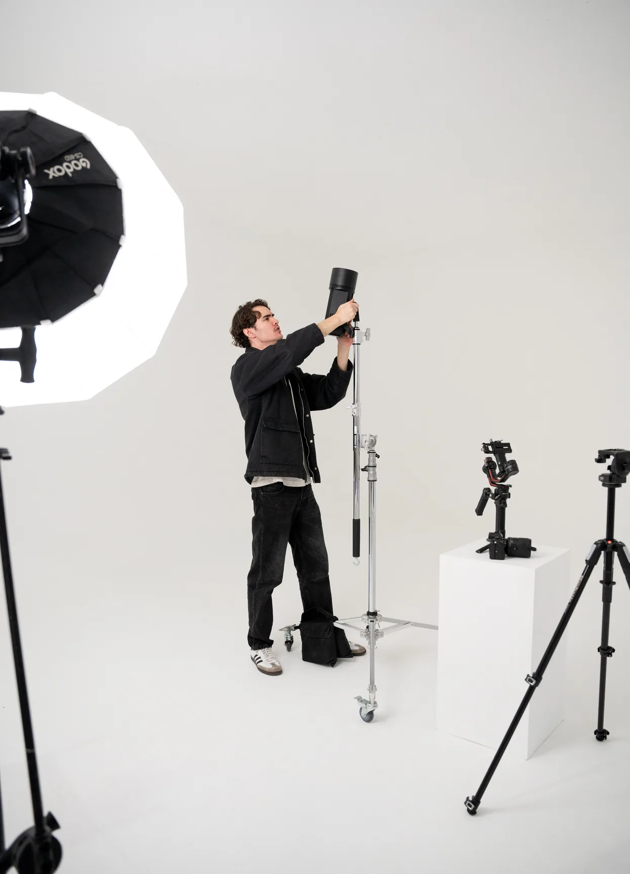 Crew member rigging a light on a stand in a white studio