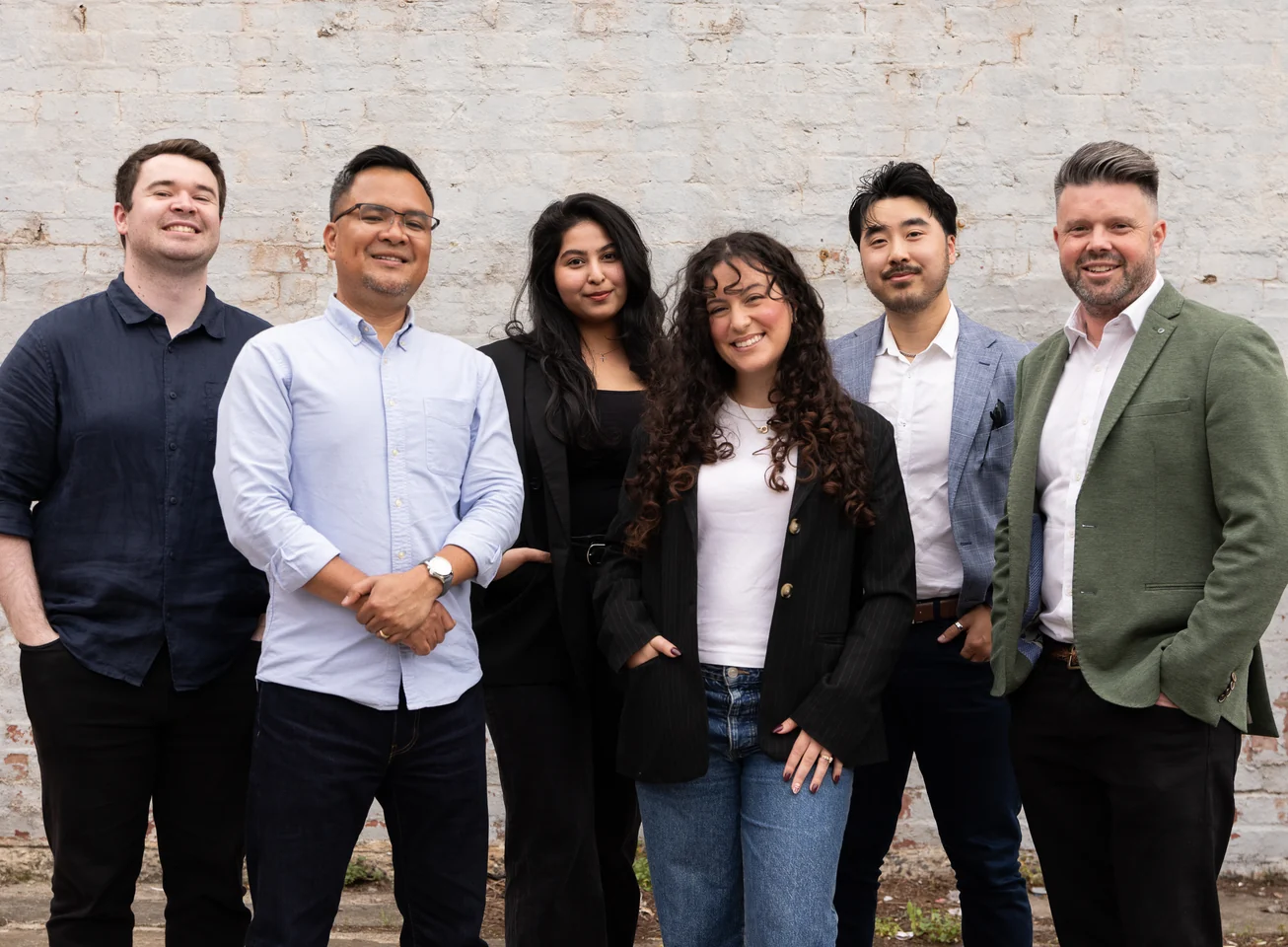 The Media Exchange team standing together in front of a white brick wall